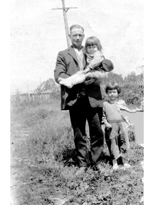 Joan Jones [standing] and sister Evelyn with neighbor Mr. England while they were living in a tent on the vacant lot that became the post office.