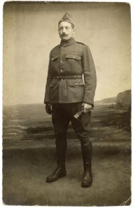 Andre Marc in a WWI uniform circa 1917 standing in front of a painted backdrop.